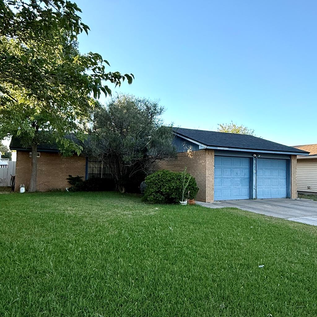 view of front facade with driveway, a front yard, a garage, and brick siding
