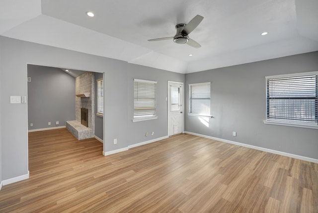 interior space featuring a healthy amount of sunlight, a fireplace, vaulted ceiling, and light wood-type flooring