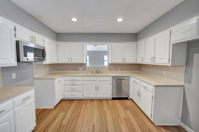 kitchen with sink, light hardwood / wood-style flooring, white cabinets, and appliances with stainless steel finishes