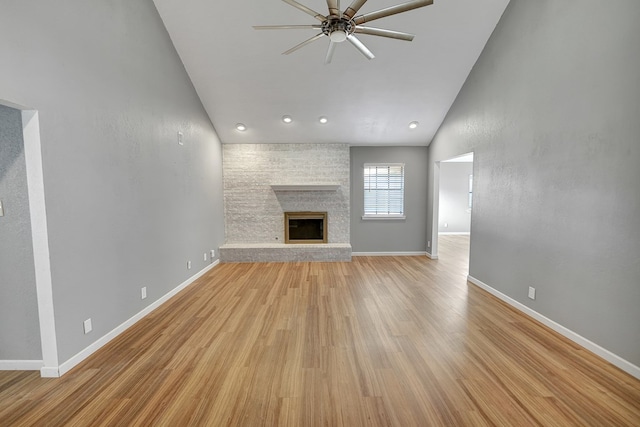 unfurnished living room with ceiling fan, a fireplace, vaulted ceiling, and light wood-type flooring