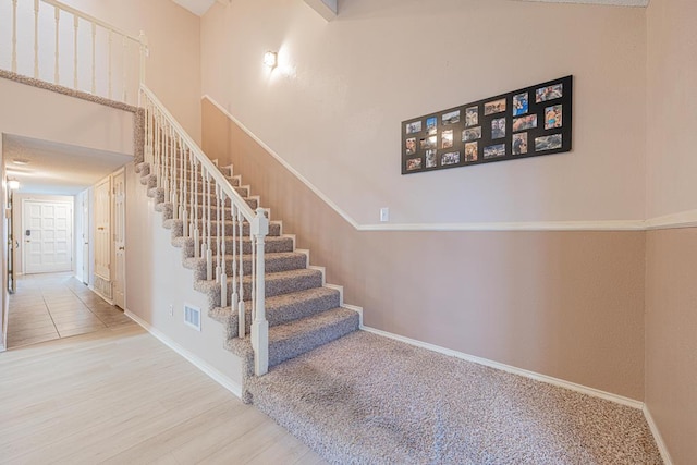 stairway with hardwood / wood-style flooring and a towering ceiling