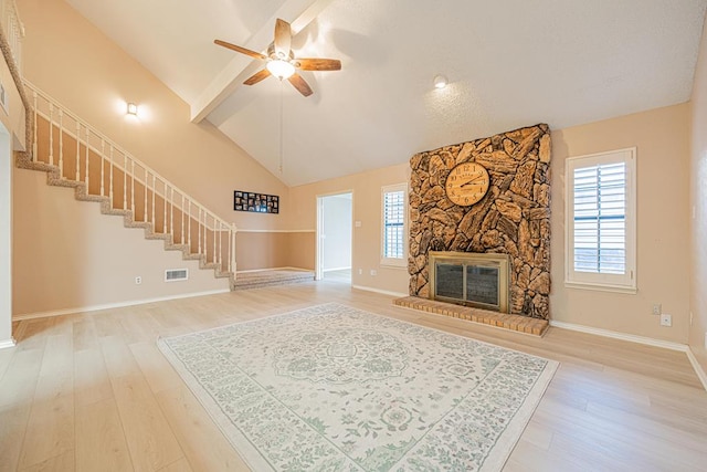 living room with ceiling fan, high vaulted ceiling, wood-type flooring, and a stone fireplace