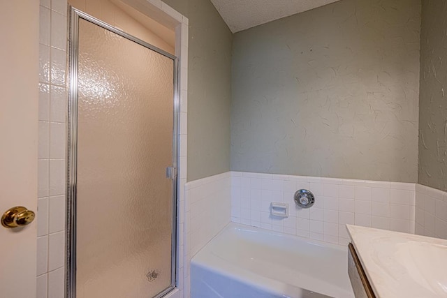 bathroom featuring a textured ceiling, separate shower and tub, and vanity