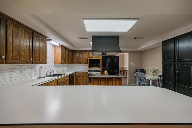 kitchen featuring black appliances, island range hood, decorative backsplash, sink, and kitchen peninsula