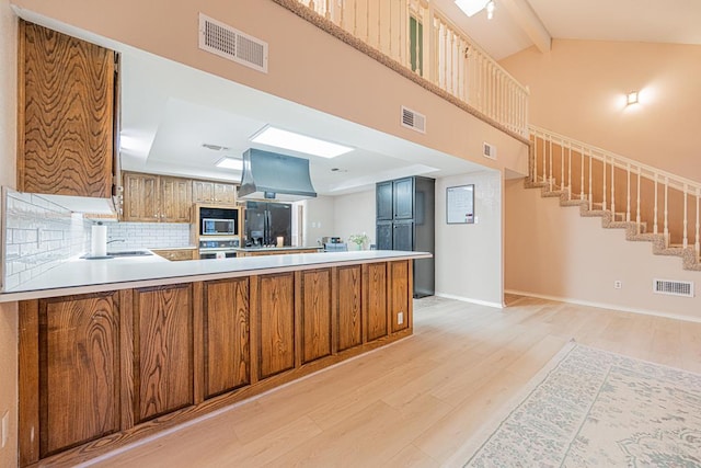 kitchen with built in microwave, island exhaust hood, black fridge, and kitchen peninsula