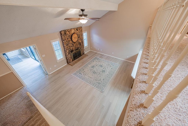 living room featuring a fireplace, hardwood / wood-style flooring, vaulted ceiling with beams, and ceiling fan