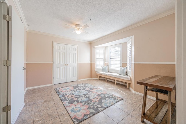 living area featuring ceiling fan, light tile patterned floors, crown molding, and a textured ceiling