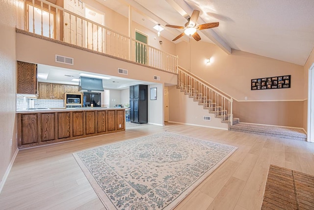 interior space featuring lofted ceiling, black fridge with ice dispenser, light wood-type flooring, ceiling fan, and tasteful backsplash