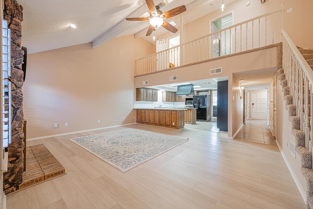 unfurnished living room with light hardwood / wood-style flooring, ceiling fan, a wealth of natural light, and a textured ceiling