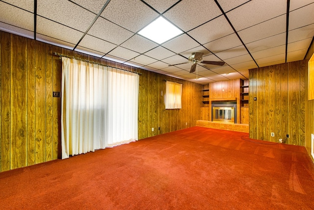 4717 W Illinois Ave, Midland, TX 79703 - unfurnished living room featuring a brick fireplace, carpet, wood walls, and ceiling fan