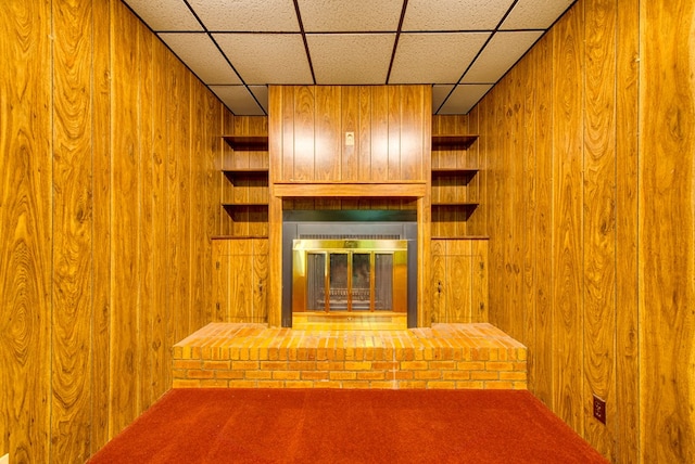 4717 W Illinois Ave, Midland, TX 79703 - unfurnished living room featuring wood walls, a fireplace, a drop ceiling, and carpet