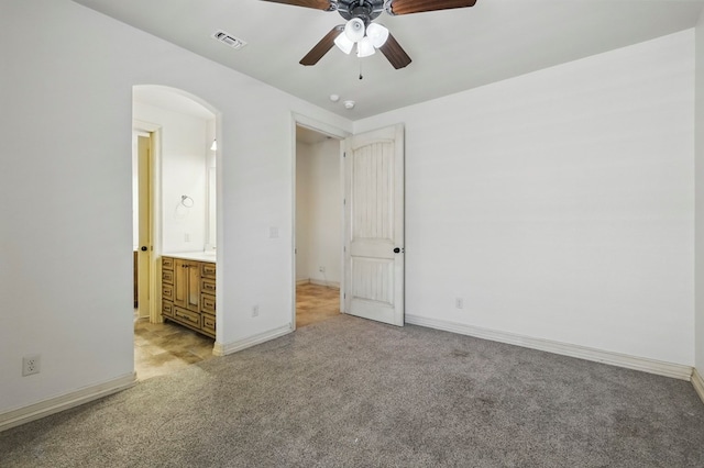 5001 Crista Ln, Midland, TX 79707 - unfurnished bedroom featuring light carpet, arched walkways, ensuite bath, baseboards, and a ceiling fan