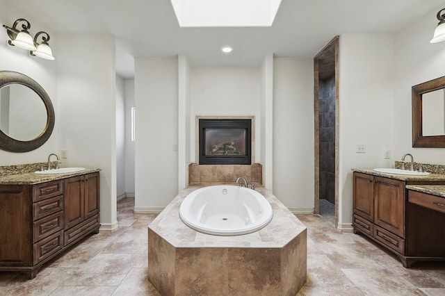 5001 Crista Ln, Midland, TX 79707 - full bathroom with a bath, a fireplace, two vanities, a skylight, and recessed lighting