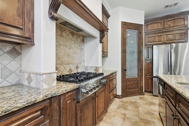 5001 Crista Ln, Midland, TX 79707 - kitchen featuring stainless steel appliances, light stone countertops, decorative backsplash, and dark brown cabinets