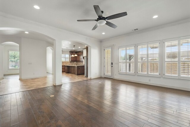 5001 Crista Ln, Midland, TX 79707 - unfurnished living room featuring arched walkways, plenty of natural light, crown molding, ceiling fan, and baseboards