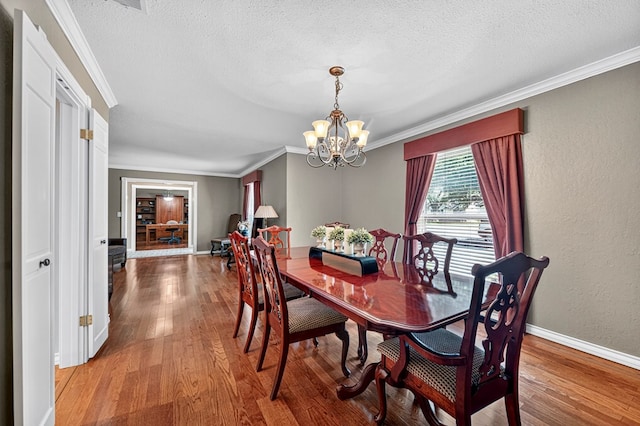2409 Stutz Pl, Midland, TX 79705 - dining area with light wood-style flooring, a chandelier, ornamental molding, and a textured ceiling