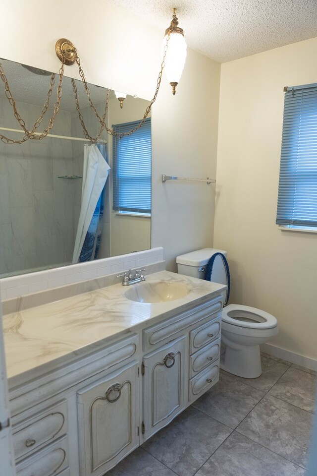 bathroom with vanity, tile patterned flooring, toilet, a textured ceiling, and walk in shower