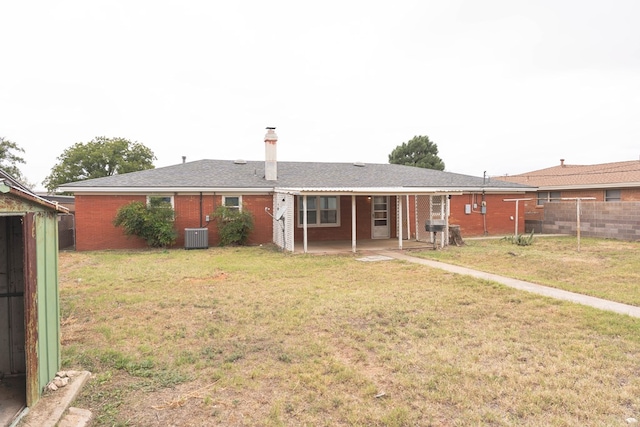 rear view of property with a yard and central AC