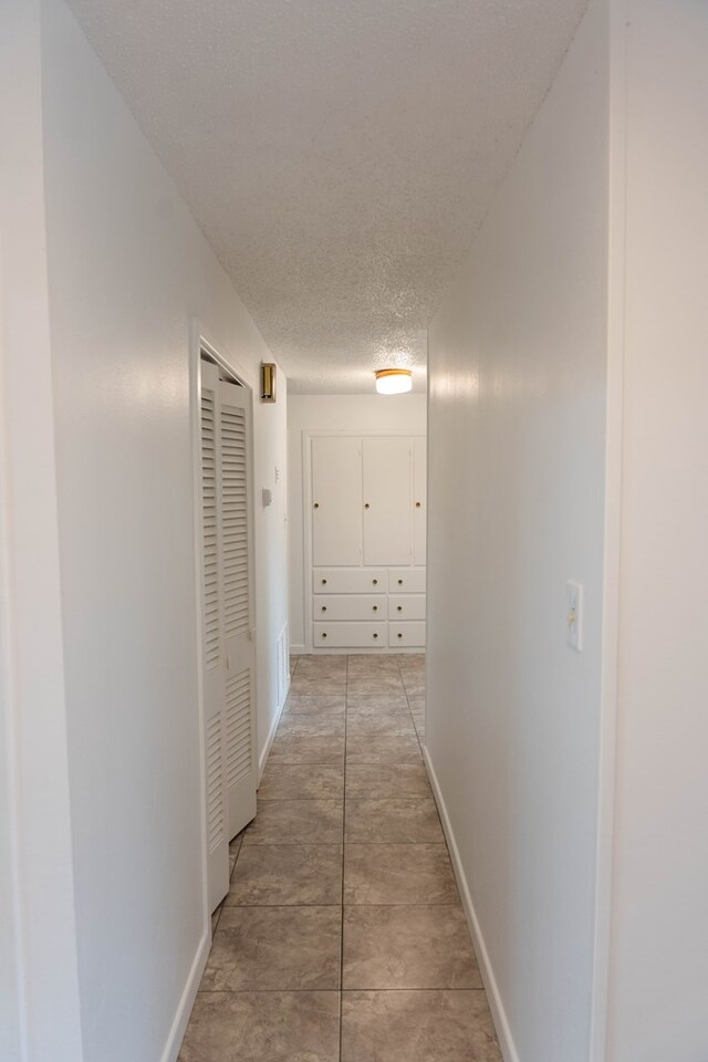 hall featuring light tile patterned floors and a textured ceiling