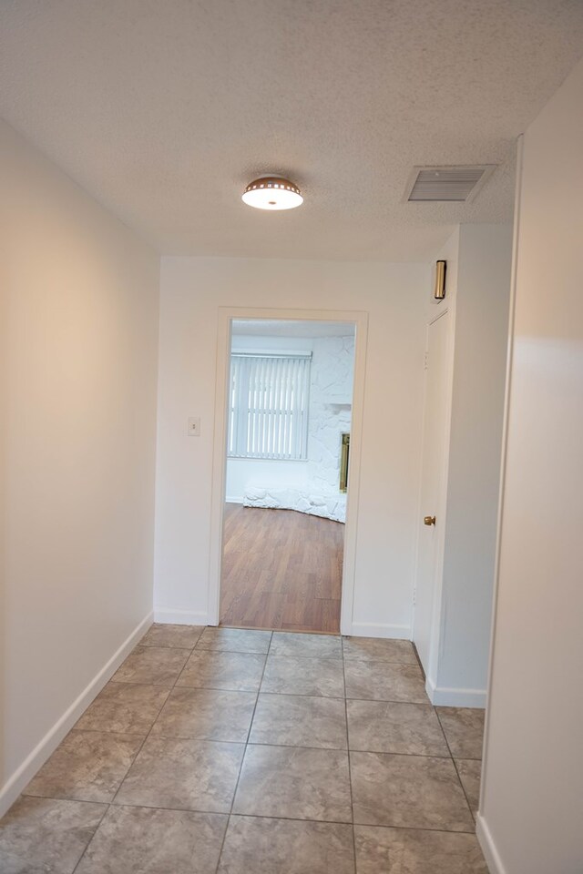 corridor featuring light wood-type flooring and a textured ceiling