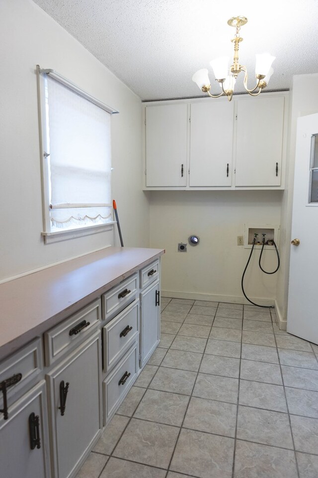 clothes washing area featuring cabinets, hookup for a washing machine, a chandelier, and light tile patterned floors