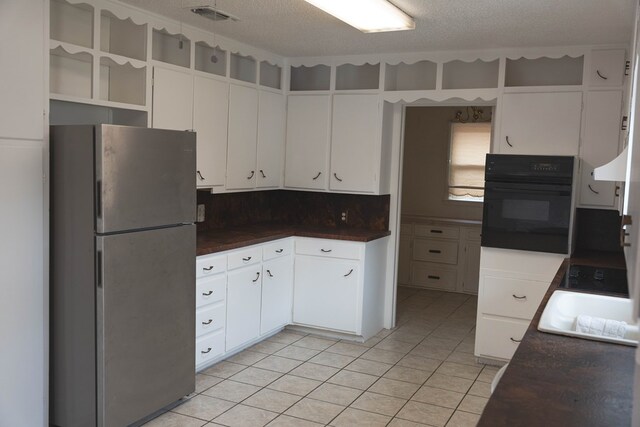 kitchen featuring tasteful backsplash, stainless steel fridge, oven, a textured ceiling, and white cabinets