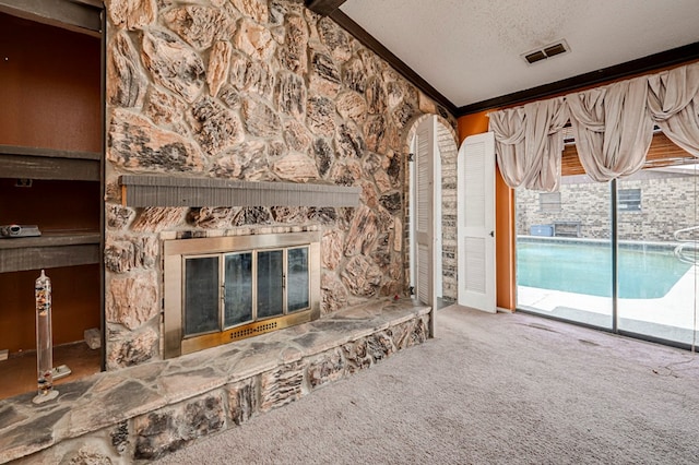unfurnished living room featuring carpet, vaulted ceiling, a fireplace, visible vents, and a textured ceiling