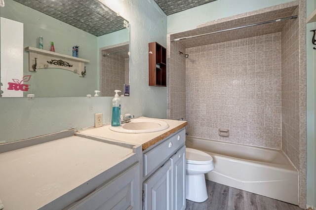 full bathroom featuring vanity, bathing tub / shower combination, toilet, a textured wall, and wood finished floors