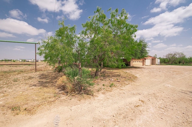 view of yard featuring an outbuilding, a rural view, and a garage