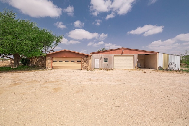 view of front of property with a detached garage and an outbuilding