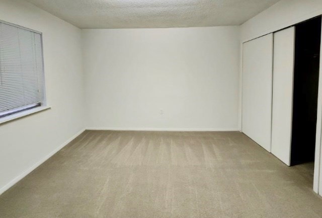 unfurnished bedroom with light carpet, a closet, and a textured ceiling