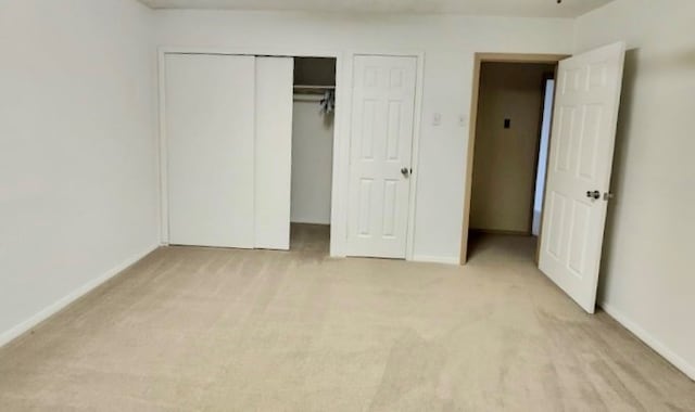 unfurnished bedroom featuring baseboards, a closet, and light colored carpet