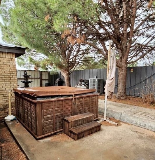 exterior space featuring central air condition unit, a hot tub, and fence