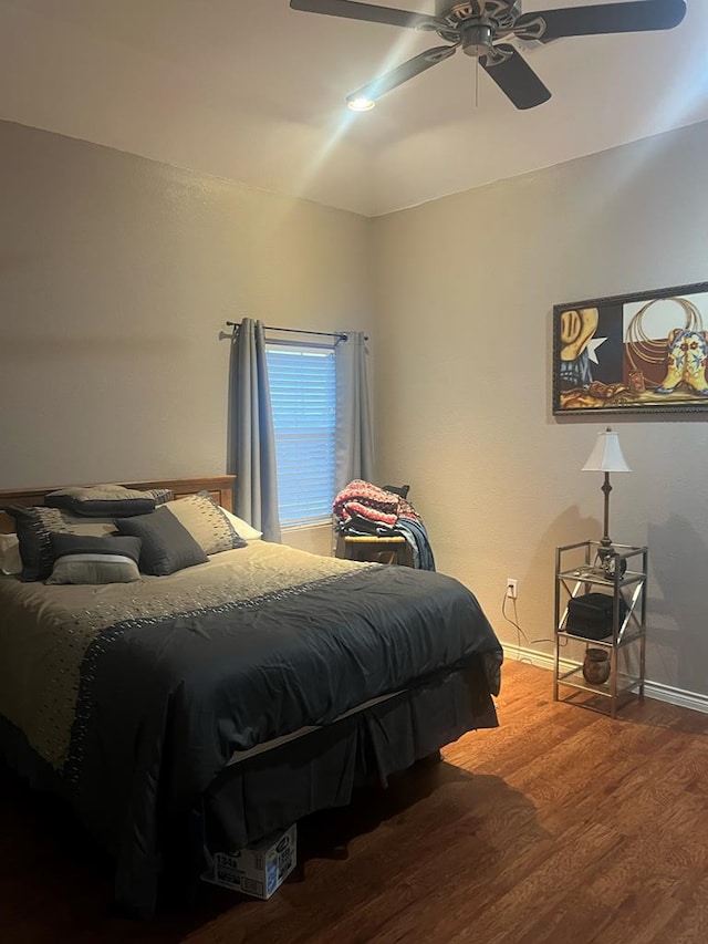 bedroom with ceiling fan, baseboards, and wood finished floors