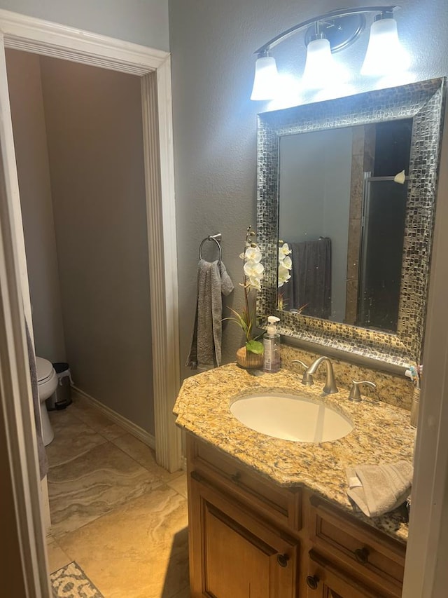 full bathroom with a shower stall, toilet, vanity, and baseboards