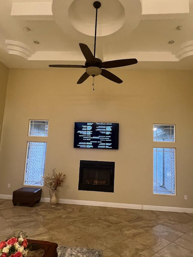 unfurnished living room with ceiling fan, a fireplace, and baseboards