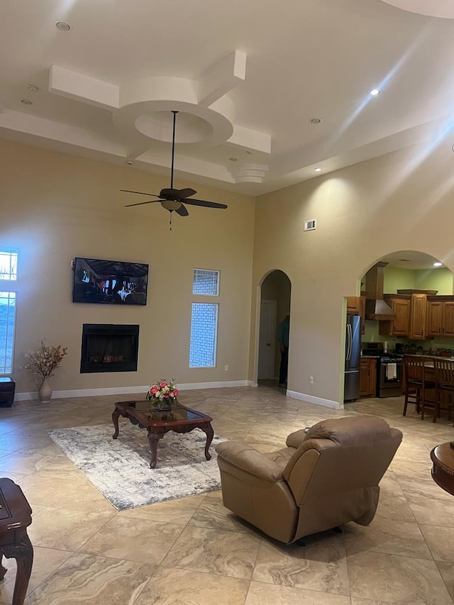 living room featuring arched walkways, a fireplace, a high ceiling, and baseboards