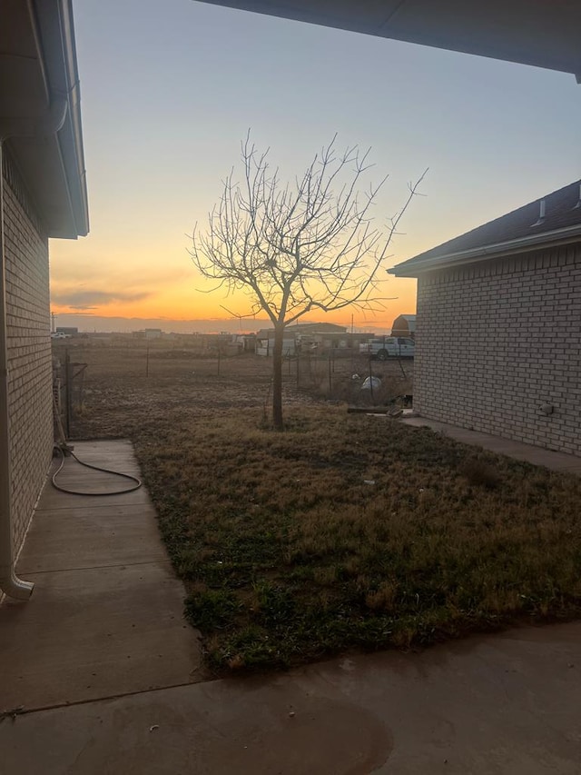 yard at dusk featuring fence