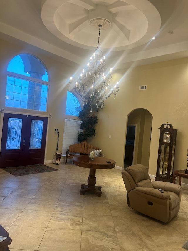 foyer entrance with a raised ceiling, a high ceiling, visible vents, and arched walkways