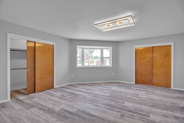 unfurnished bedroom featuring a closet, light wood-type flooring, and baseboards