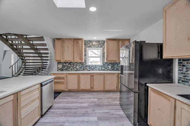 kitchen featuring decorative backsplash, freestanding refrigerator, light brown cabinets, and dishwasher