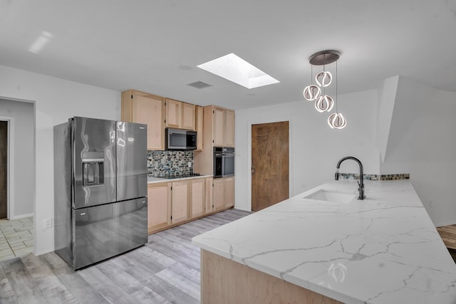 kitchen featuring visible vents, black appliances, a skylight, a sink, and light brown cabinets