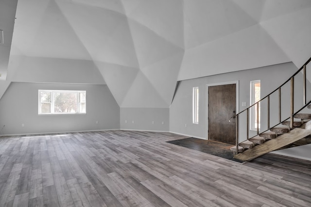 bonus room with stairway, a high ceiling, baseboards, and wood finished floors