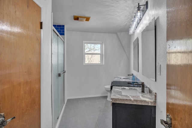 bathroom featuring a shower stall, toilet, a sink, double vanity, and baseboards