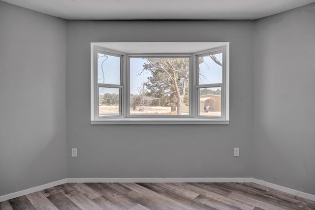 unfurnished room featuring a wealth of natural light, wood finished floors, and baseboards