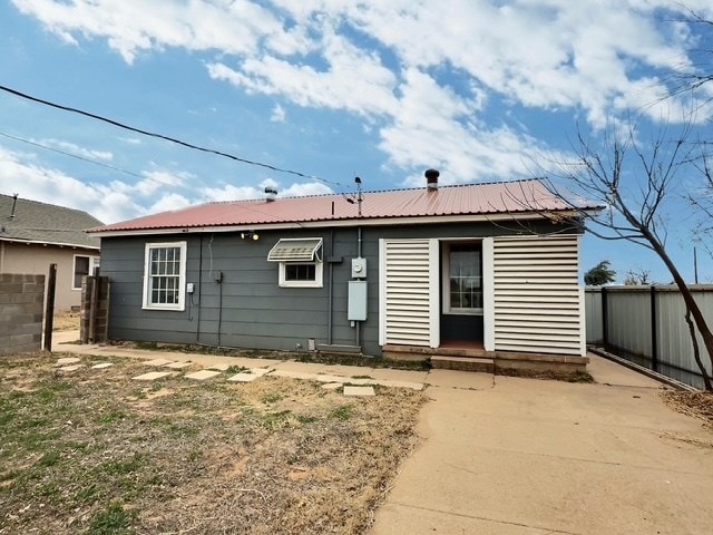 back of house with metal roof and fence