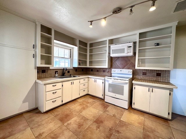 kitchen with white appliances, light countertops, a sink, and white cabinetry