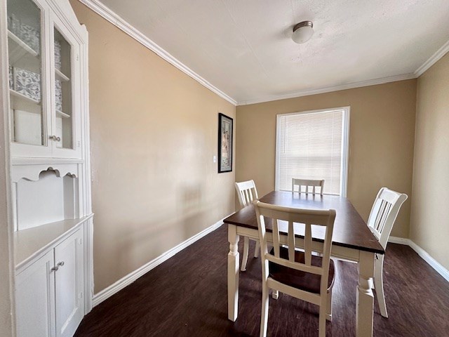 dining room with ornamental molding, dark wood-type flooring, and baseboards