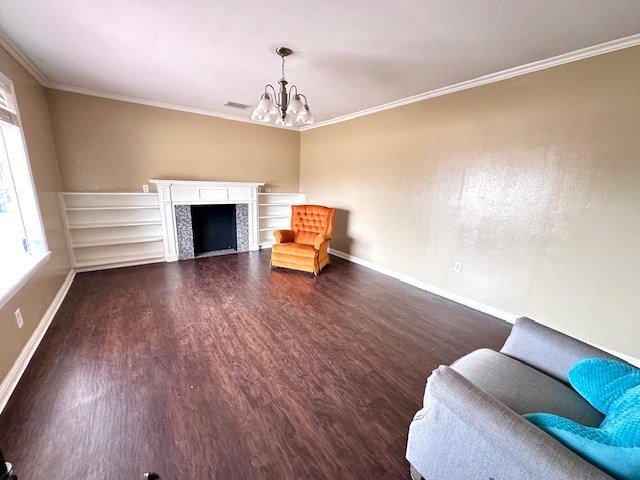 unfurnished room featuring crown molding, a notable chandelier, dark wood finished floors, and baseboards