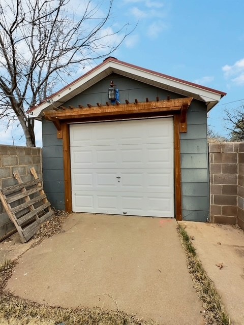 detached garage with fence and concrete driveway